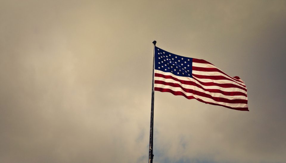 A veteran standing before the American flag.